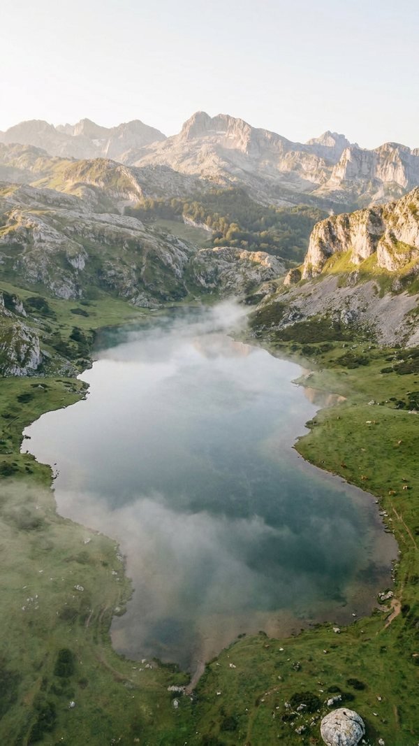 Vista aérea de un lago de montaña entre la niebla